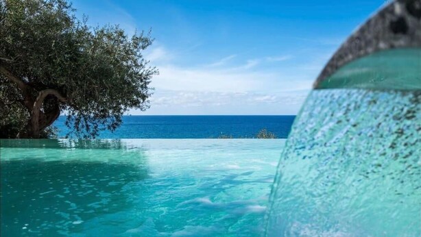 A clear blue pool with a view of the ocean and a tree. - Sea Pool and Relax Cefalù (Cefalù)