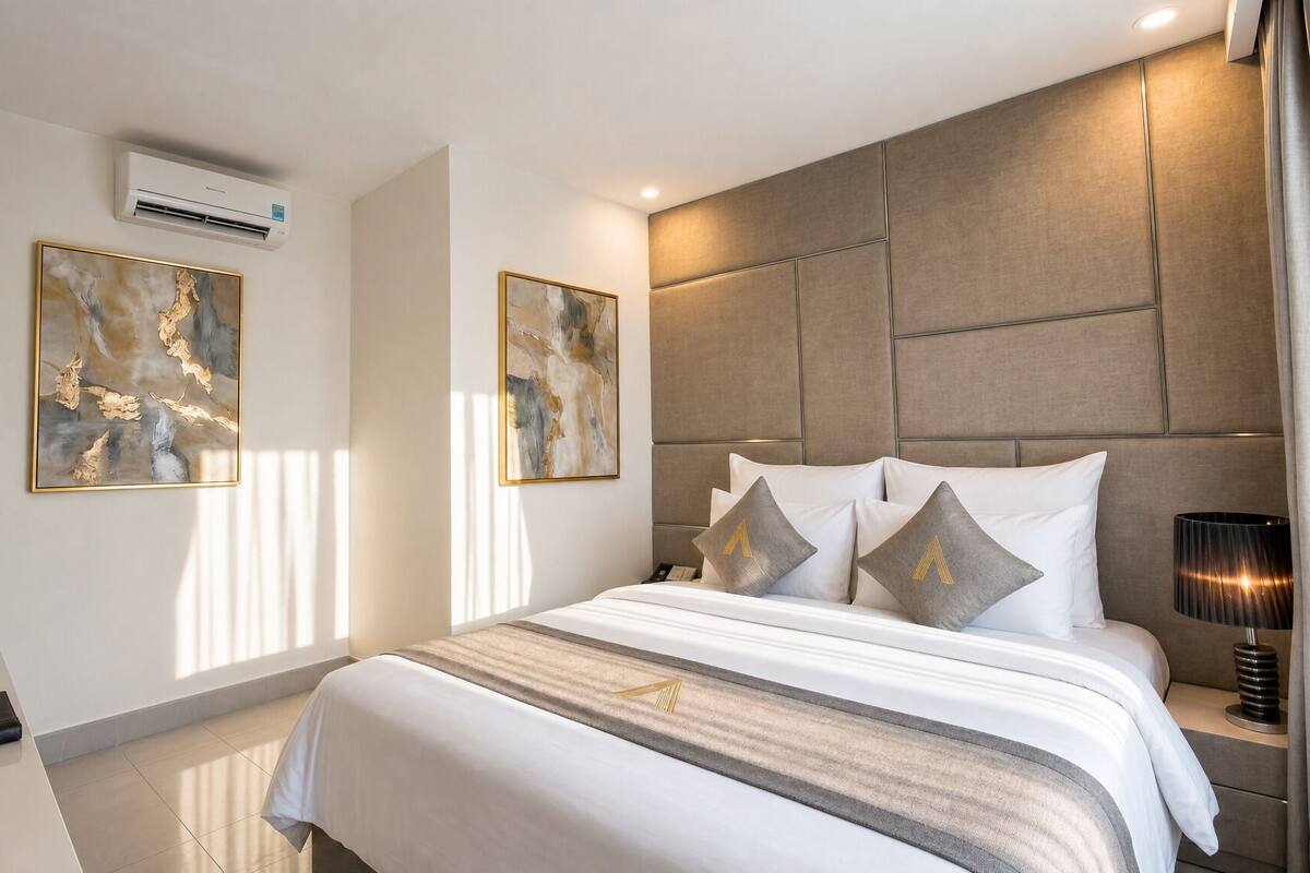 A hotel room with a large bed, a flat-screen TV, two abstract paintings, a modern headboard, and a bedside lamp.