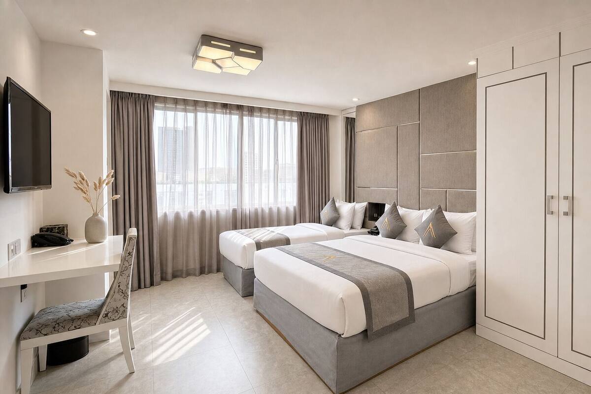 A modern hotel room with two beds, a desk, a TV, and a wardrobe.