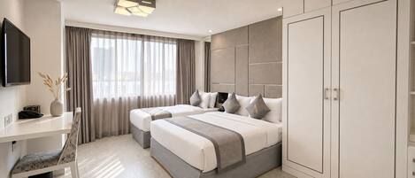 A modern hotel room with two beds, a desk, a TV, and a wardrobe.