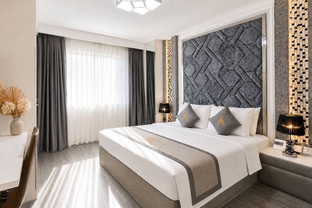 A modern hotel room with a large bed, a desk with a phone, and a TV.