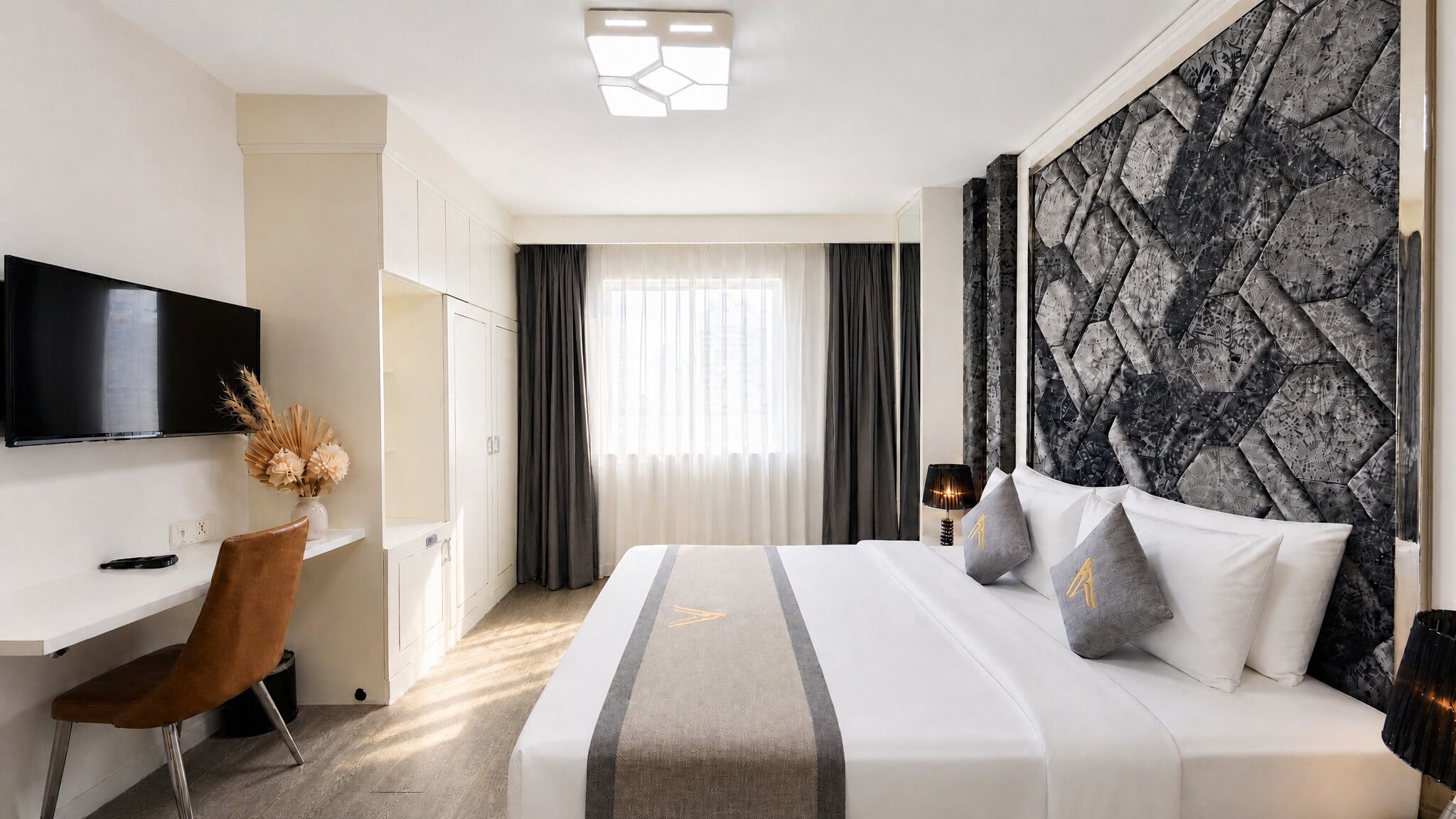 Una habitación de hotel con cama, escritorio, televisión y ventana con cortinas.