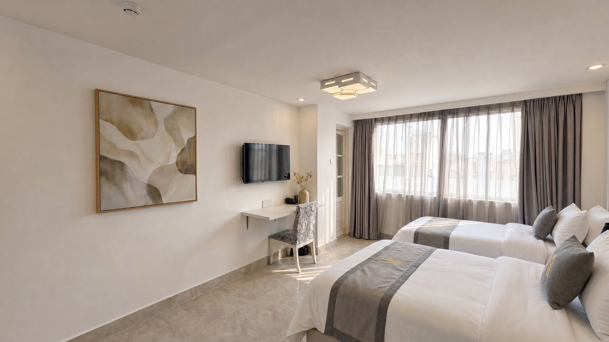 Een hotelkamer met twee bedden, een bureau, een stoel, een televisie en een groot raam met gordijnen.