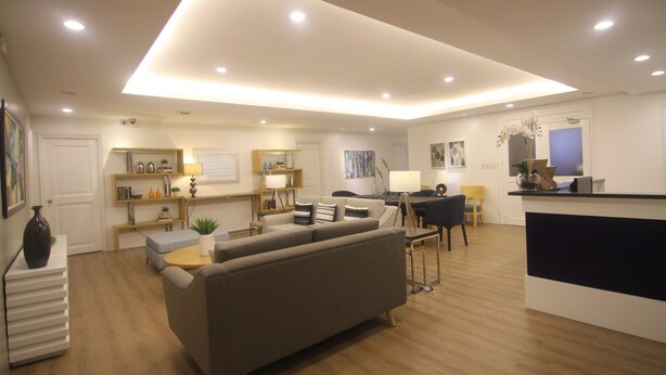 A modern living room with a sofa, a dining table, and a kitchen area with a counter. - Bryan Condominium Suites (Makati)