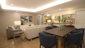 A modern living room with a sofa, a dining table, and chairs. - Bryan Condominium Suites (Makati)