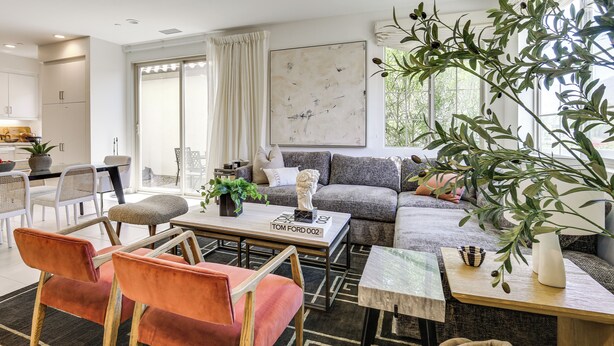 Ein modernes Wohnzimmer mit einer Couch, Sesseln, einem Couchtisch und einem Essbereich mit Stühlen und einem Tisch.