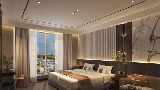 Una habitación de hotel moderna con una cama grande, un sofá, una mesa de centro y vistas a la ciudad.