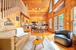Ein Holzblockhaus-Interieur mit Wohnzimmer, Küche und Essbereich.