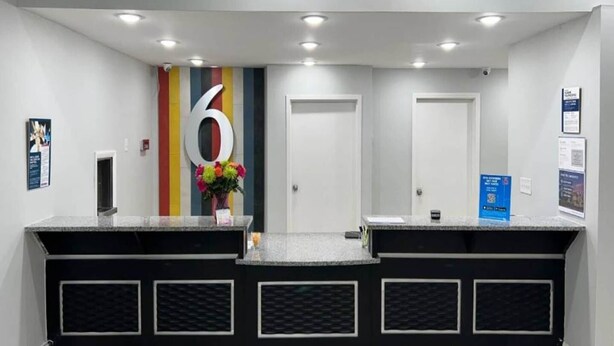 A reception area with a counter, a number '6' sign, and a door. - 1 King Bed|Non-Smoking,Micfridge (West Columbia)