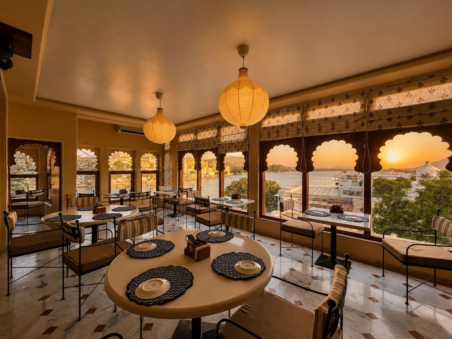 Un restaurante con mesas redondas, sillas y lámparas de papel decorativas.