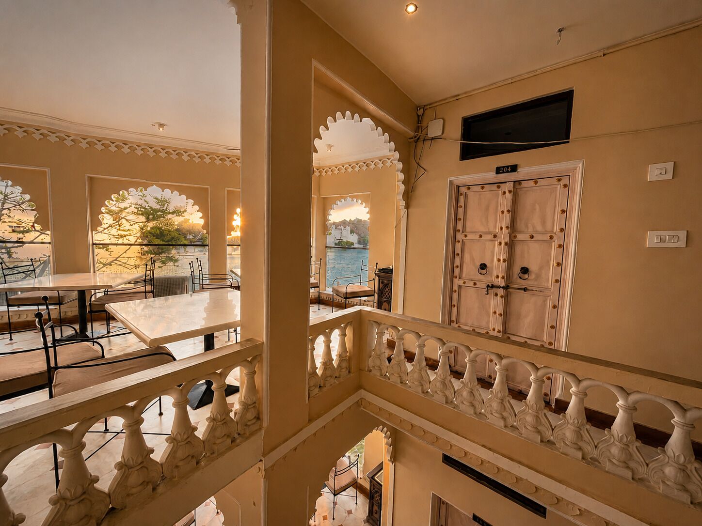 A multi-level hotel interior with a balcony, ornate railings, and a view of the sea.