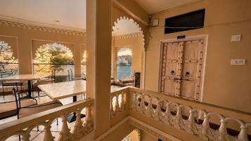 A multi-level hotel interior with a balcony, ornate railings, and a view of the sea.