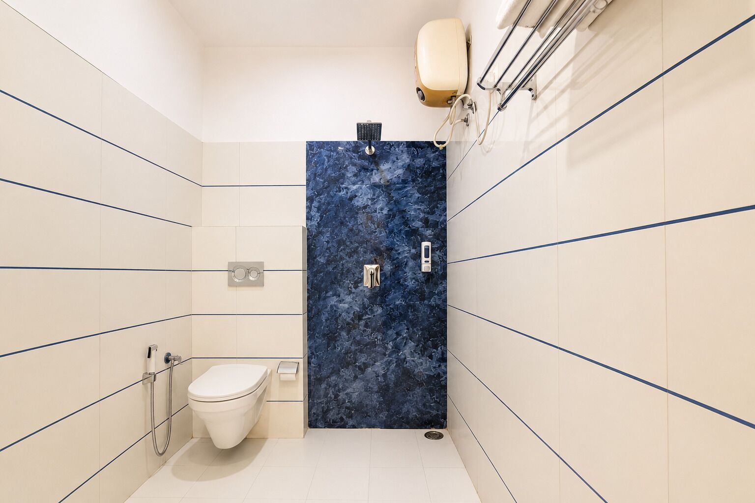 A bathroom with a toilet, a blue marble wall, and a hand dryer.