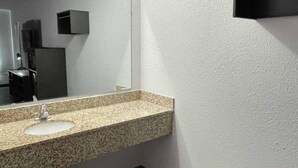 Un baño con lavamanos de encimera de granito, un espejo y piso oscuro.