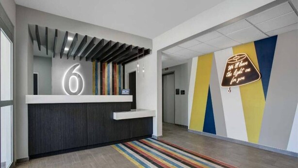 A reception desk with a large number '6' sign, a modern design with a dark counter, and a colorful striped rug. - 1 King Bed|Nsmk|Kitchen,Shower (Monahans)