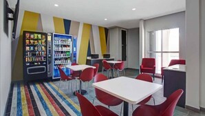 A modern dining area with red chairs, white tables, vending machines, and a colorful striped carpet. - 1 King Bed|Nsmk|Kitchen,Shower (Monahans)