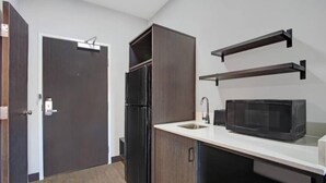 A compact kitchen with a refrigerator, microwave, and a white countertop. - 1 King Bed|Nsmk|Kitchen,Shower (Monahans)