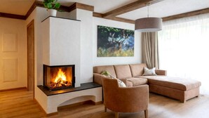 A modern living room with a fireplace, a sectional sofa, and a painting on the wall. - Rauris Penthouse with Sauna (Rauris)