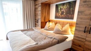 A bedroom with a bed, headboard, and a painting on the wall. - Rauris Penthouse with Sauna (Rauris)