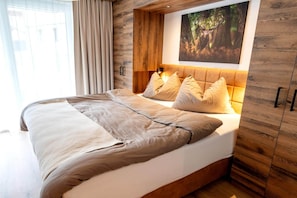 A bedroom with a bed, headboard, and a painting on the wall.