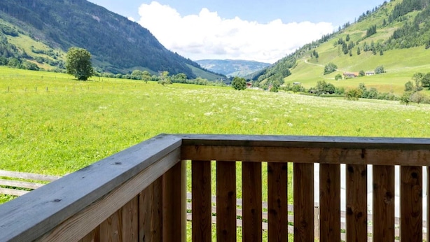 A wooden deck with a view of a green valley and mountains. - Rauris Penthouse with Sauna (Rauris)