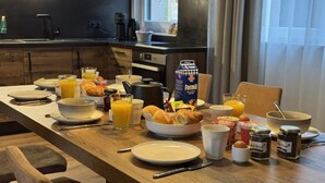 A breakfast setting with a variety of food items, including croissants, eggs, and juice, on a wooden table in a kitchen. - Rauris Penthouse with Sauna (Rauris)