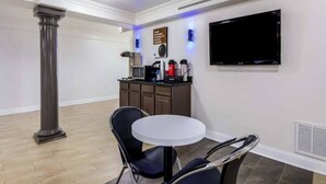 Une pièce comprenant une table ronde, deux chaises, un téléviseur, une machine à café et un meuble.