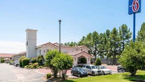 Un motel avec une grande enseigne, un parking et un bâtiment dont le toit est recouvert de tuiles rouges.