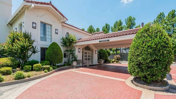 A building with a covered entrance, a paved driveway, and well-maintained landscaping. - 1 King Bed|Non-Smoking (North Little Rock)