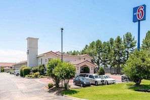 A motel with a parking lot, a sign indicating it's a Motel 6, and a building with a red-tiled roof.