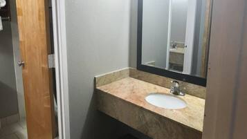 Une salle de bain avec un lavabo en marbre, un miroir et une porte.