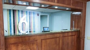 A reception desk with a large number '6' sign, a computer, and wooden paneling.