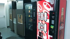 A vending machine with a Coca-Cola logo, a digital display, and a payment interface.