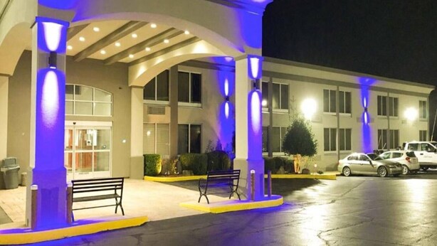 A hotel entrance with a covered walkway, a bench, and a parking area.