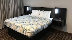 A hotel room with a bed, a nightstand, a lamp, and a curtain.