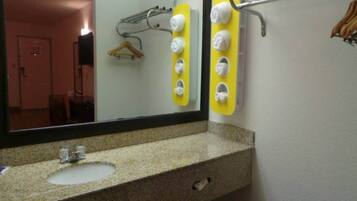 A bathroom with a granite countertop, a sink, a mirror, and a towel rack with multiple towels.