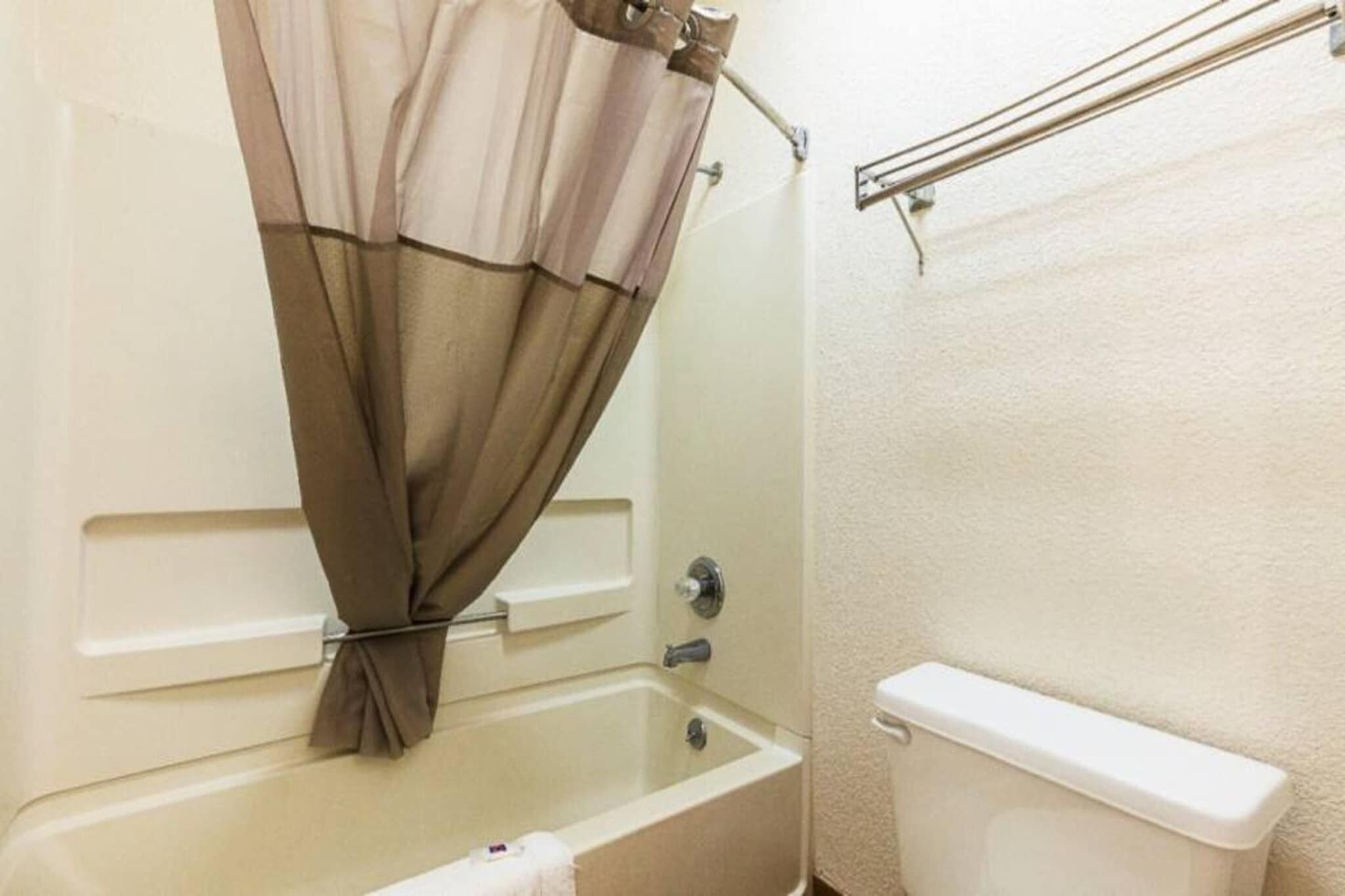 A bathroom with a bathtub, toilet, and shower curtain.