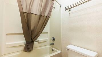 A bathroom with a bathtub, toilet, and shower curtain.