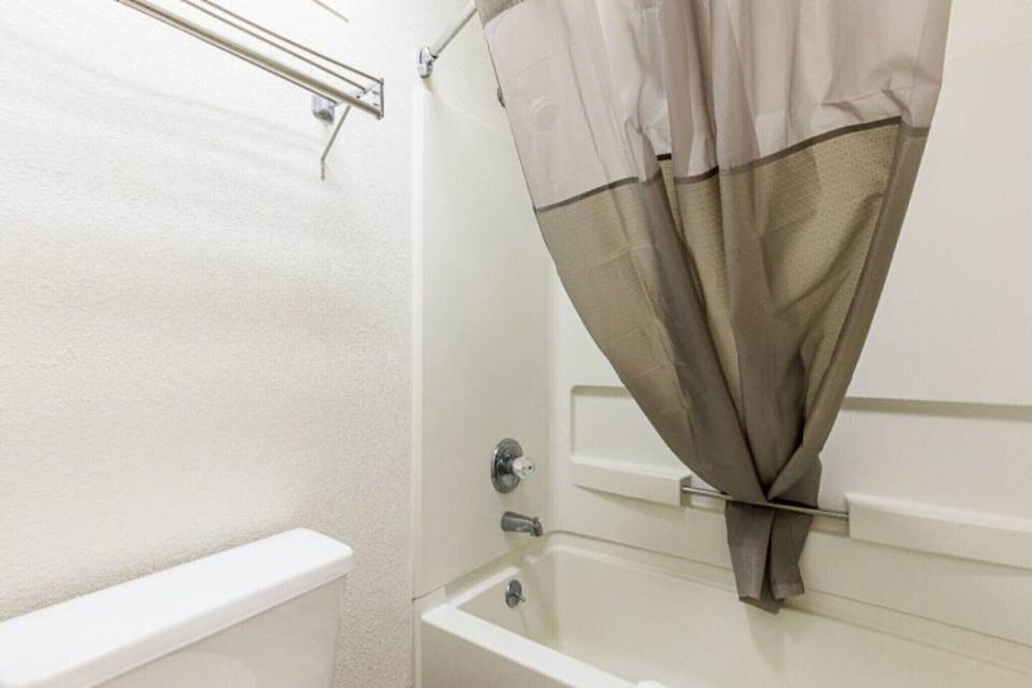 Ein Badezimmer mit Badewanne, Duschvorhang und Handtuchhalter.