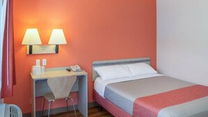 Una habitación de hotel con una cama, un escritorio con dos lámparas, una silla y un teléfono.