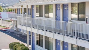 A motel with a two-story structure, numbered rooms, and a balcony.