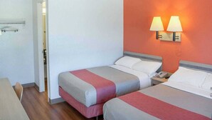 A hotel room with two beds, a wooden floor, a white wall, and a red accent wall with two wall lamps. - 2 Full Beds | Mini Fridge (Ukiah)