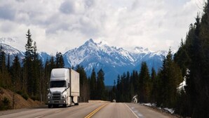 A road with a large truck and a smaller vehicle, surrounded by snow-capped mountains and dense forests. - 2 Full Beds|Non Smoking (Ukiah)