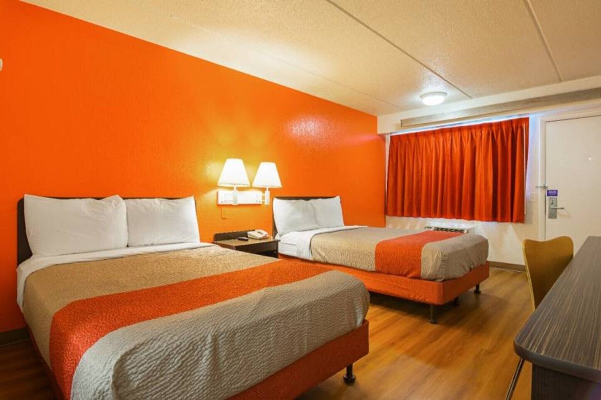 A hotel room with two beds, a desk, and a chair.
