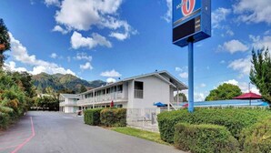 Um motel com um letreiro grande, estacionamento e um edifício com varanda.