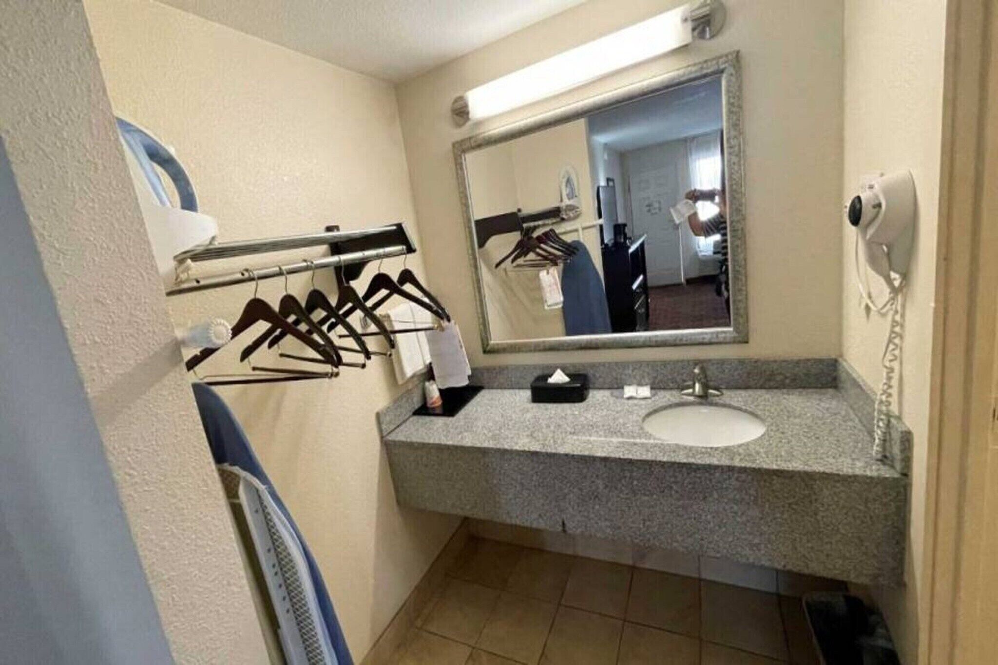 Ein Badezimmer mit Waschbecken, Spiegel, Handtuchhalter und einem Föhn.