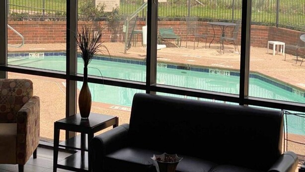 A room with a large window overlooking a swimming pool and a fenced outdoor area. - 2 Queen Beds | Smoking, Micfridge (Oklahoma City OK)