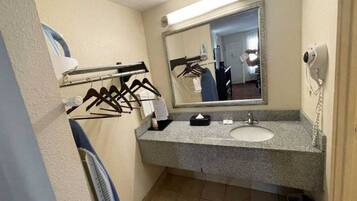 A bathroom with a sink, mirror, towel rack, and a hairdryer.
