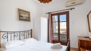 A bedroom with a bed, a wooden desk, a mirror, a painting, and a window with curtains. - Apartment 'Double Room with Sea View' with Shared Garden and Wi-Fi (Mpatsi)