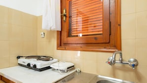 A kitchen with a stove, a sink, and a window with wooden blinds. - Apartment 'Double Room with Sea View' with Shared Garden and Wi-Fi (Mpatsi)